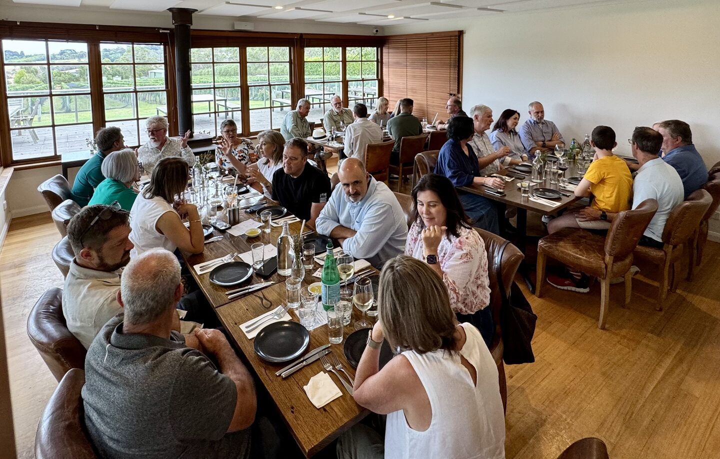 ZEEKR owners and guests sharing a long lunch together at tables beside large windows overlooking the countryside.